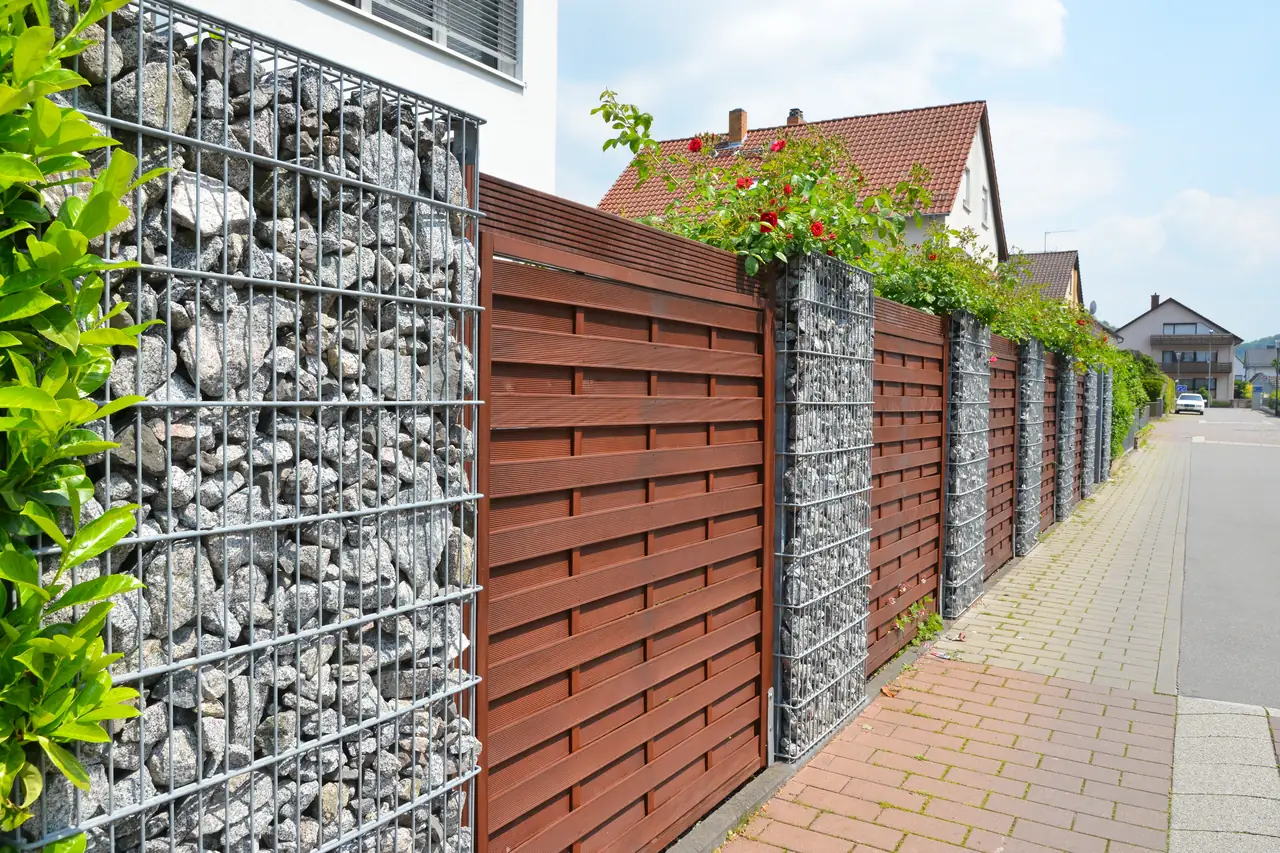 Sichtschutzzaun aus Holz und Gabionen entlang einer Grundstücksgrenze